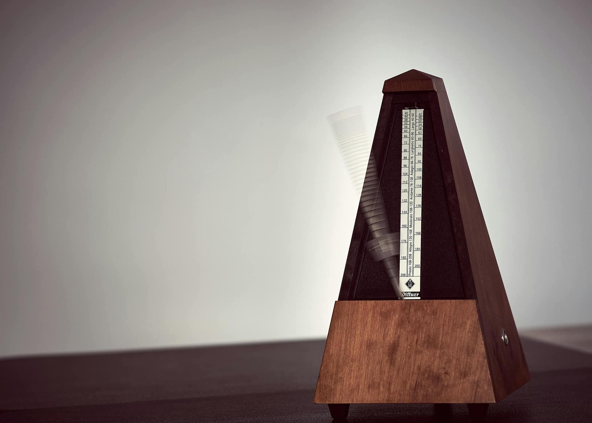 A close-up image of a wooden metronome in motion, symbolizing precision in music practice.